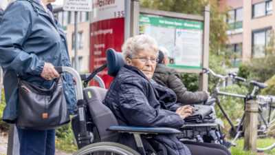 vrouw duwt bejaarde vrouw voort in rolstoel